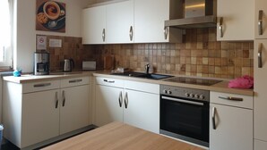 A modern kitchen with white cabinets, a stainless steel oven, and a tiled backsplash. - Pension Zum Adler (Hünstetten)