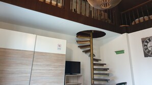 A spiral staircase with a modern design, a television on a stand, and a clock on the wall. - Pension Zum Adler (Hünstetten)