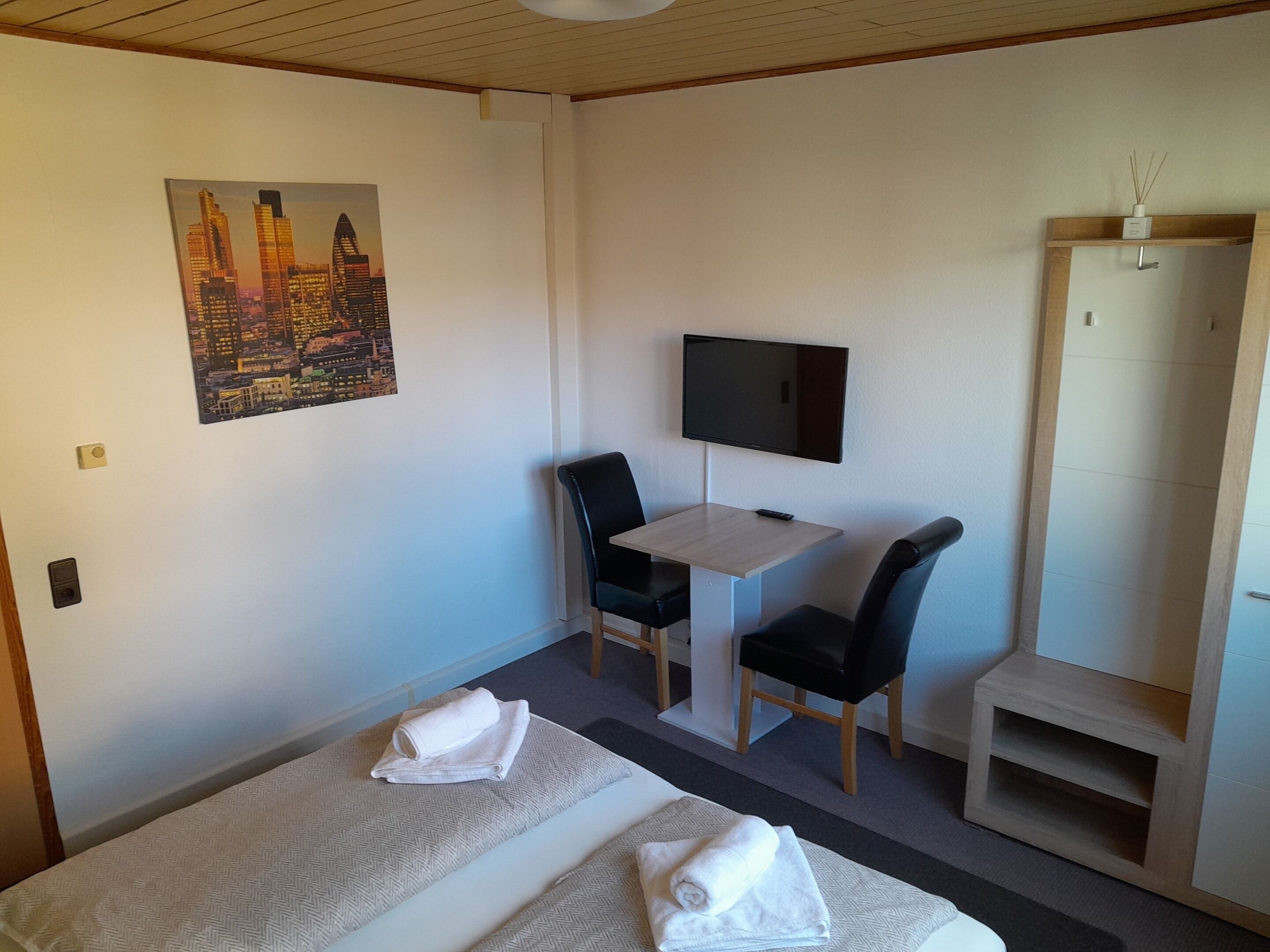 A hotel room with two beds, a desk with a chair, a TV, and a wardrobe.