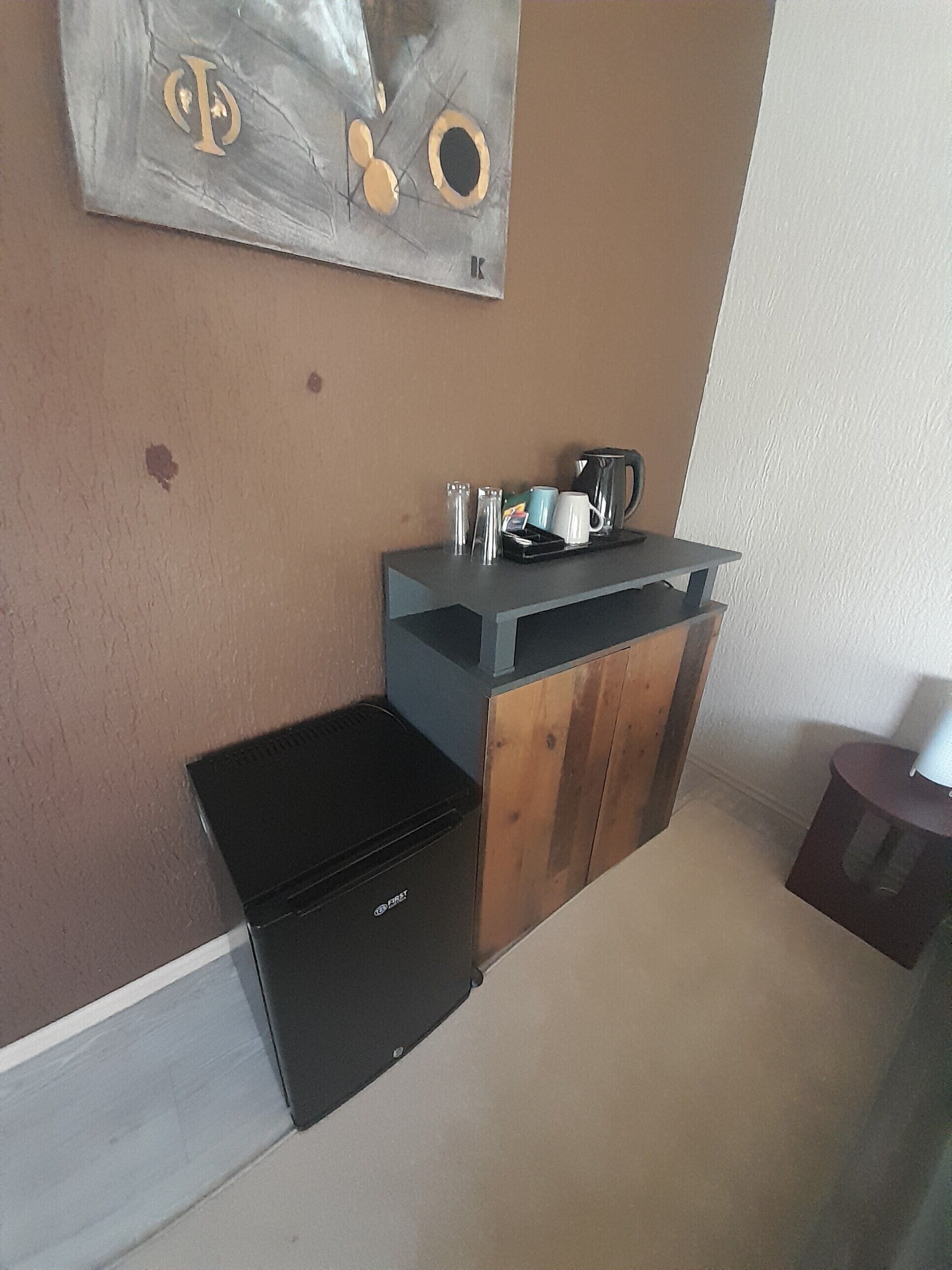 A compact kitchenette with a black refrigerator, a coffee maker, and a small sink.
