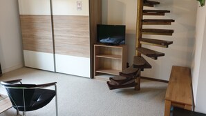 A room with a built-in wardrobe, a TV on a shelf, a cat tree, and a chair. - Pension Zum Adler (Hünstetten)