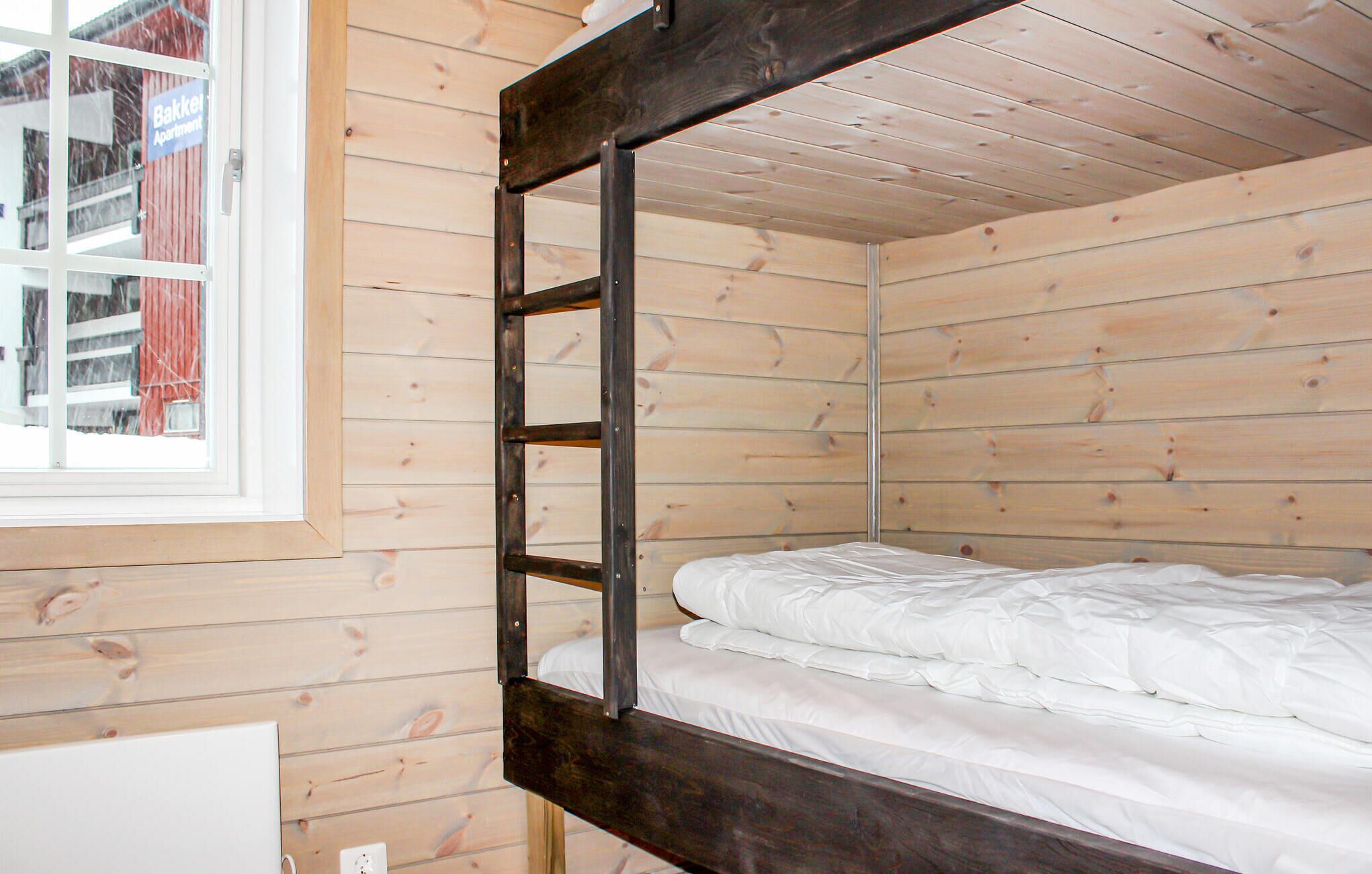 Una cama litera en una habitación de madera con ventana.