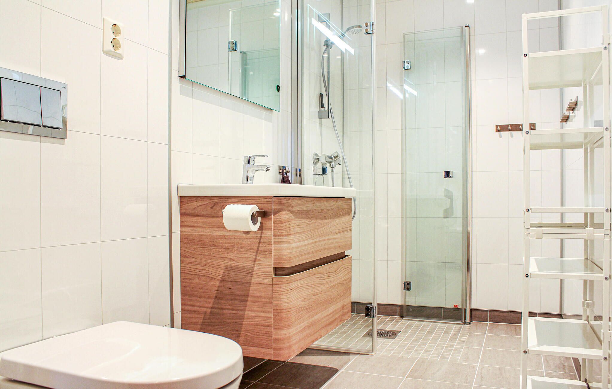 A modern bathroom with a wooden vanity, a glass shower enclosure, and a white toilet.