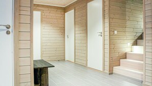Ein Flur mit Holzwandverkleidung, Fliesenboden und einer Treppe, die in ein Obergeschoss führt.