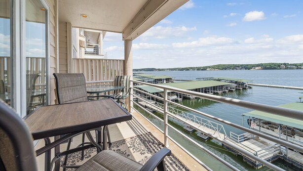 A balcony with a table and chairs overlooking a marina with docks and boats. - Emerald Bay 250 - Walk in level 2 bdrm condo (Lake Ozark)