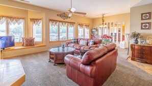 A spacious living room with a leather sofa, a glass coffee table, and a ceiling fan. - Emerald Bay 250 - Walk in level 2 bdrm condo (Lake Ozark)