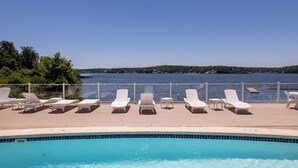A poolside area with lounge chairs and a view of a lake. - Emerald Bay 250 - Walk in level 2 bdrm condo (Lake Ozark)