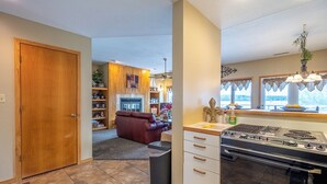 A kitchen with a stove, oven, and a dining area with a red sofa. - Emerald Bay 250 - Walk in level 2 bdrm condo (Lake Ozark)