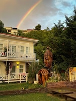 A building with a balcony, a large Buddha statue, and a rainbow in the sky.