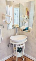 A bathroom with a white sink, a mirror, and a hairdryer on the wall.
