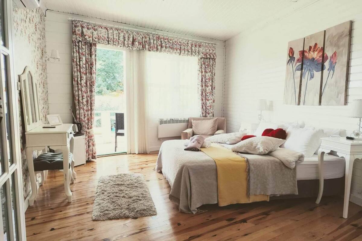A bedroom with a bed, bedside tables, a desk, a chair, and a window with curtains.