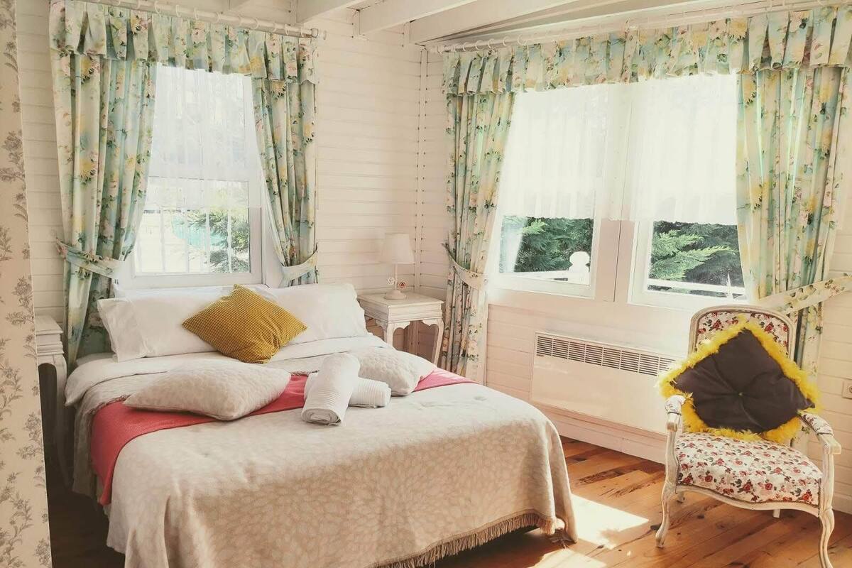 A bedroom with a bed, a chair, and a window with curtains.
