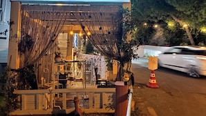 Un restaurante llamado "Lotus restaurant & home" con un área de asientos al aire libre de estilo rústico, una valla de madera y luces colgantes.