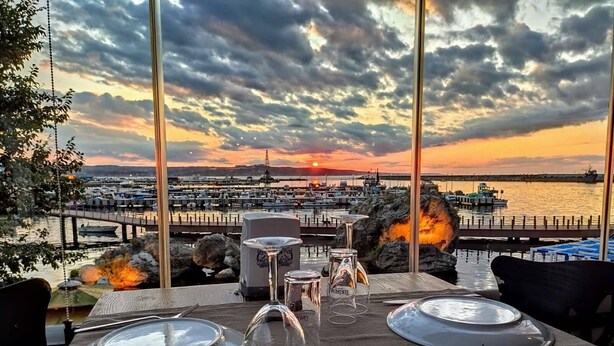 Mesa para dos con vista a un puerto deportivo y al atardecer.
