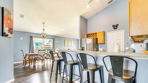 A modern kitchen with a bar area, wooden flooring, and a dining set. - 15 Mi to Disney: Home w/ Pool & Lanai in Davenport (Davenport)
