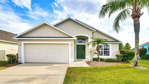 A single-story house with a white garage, a green front door, and a small front yard with a palm tree. - 15 Mi to Disney: Home w/ Pool & Lanai in Davenport (Davenport)