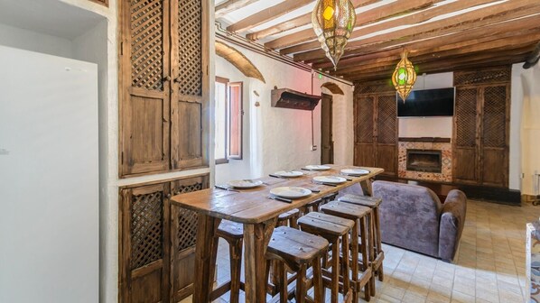 Un interno rustico con un tavolo da pranzo in legno, sgabelli da bar e un camino.