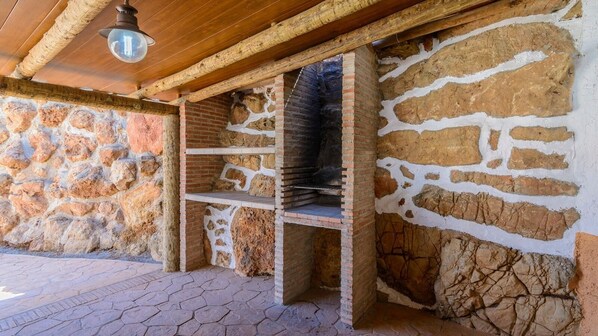 Un muro de piedra con un horno de ladrillo y techo de madera.