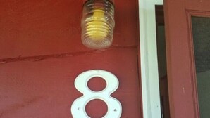 A red door with a white number '8' sign and a glass bottle on the wall. - The Gold Eagle Cabin (Lake George)