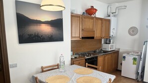 A kitchen with wooden cabinets, a stove, a sink, and a refrigerator. - App.with garden, WI-FI free, automatic gate, covered garage, air conditioning  (Bellagio)