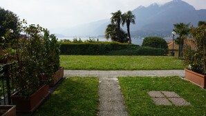 A pathway leading to a grassy area with a mountain view in the background. - App.with garden, WI-FI free, automatic gate, covered garage, air conditioning  (Bellagio)