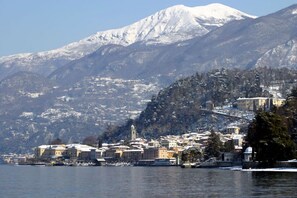 Uma cidade costeira com edifícios históricos, uma igreja imponente e uma montanha coberta de neve ao fundo.