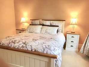 A bedroom with a bed, two bedside tables with lamps, a nightstand, and a curtain. - Burnie Brae circa 1908 - Netflix, Wifi, Air Con, Quiet Area, with 2 X Queen Beds (Katoomba)