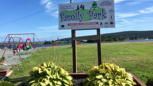 A sign for a family park with a swing set and a lake in the background. - Saltbox cottage (Clarke's Beach)