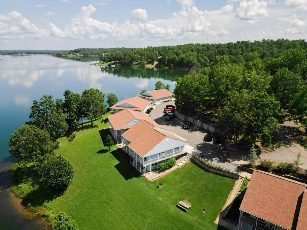 A lakeside property with multiple buildings, a parking area, and a well-maintained lawn.