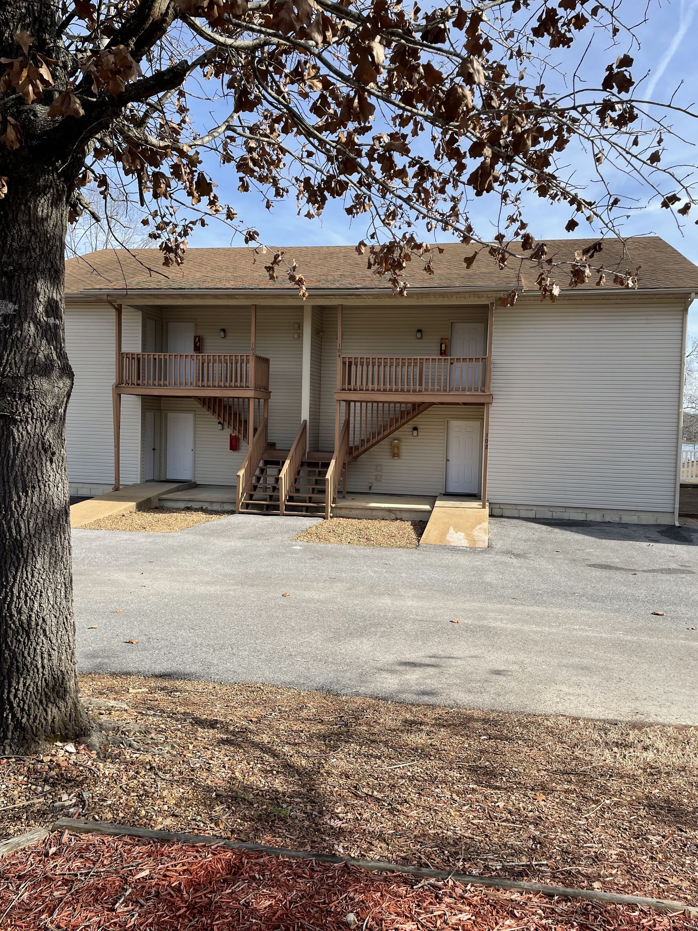 A two-story motel with a central staircase, a covered front porch, and a parking lot.