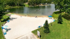 A beach with a sandy shore, a lake, and a grassy area with trees. - Crown Point Resort (Horseshoe Bend)