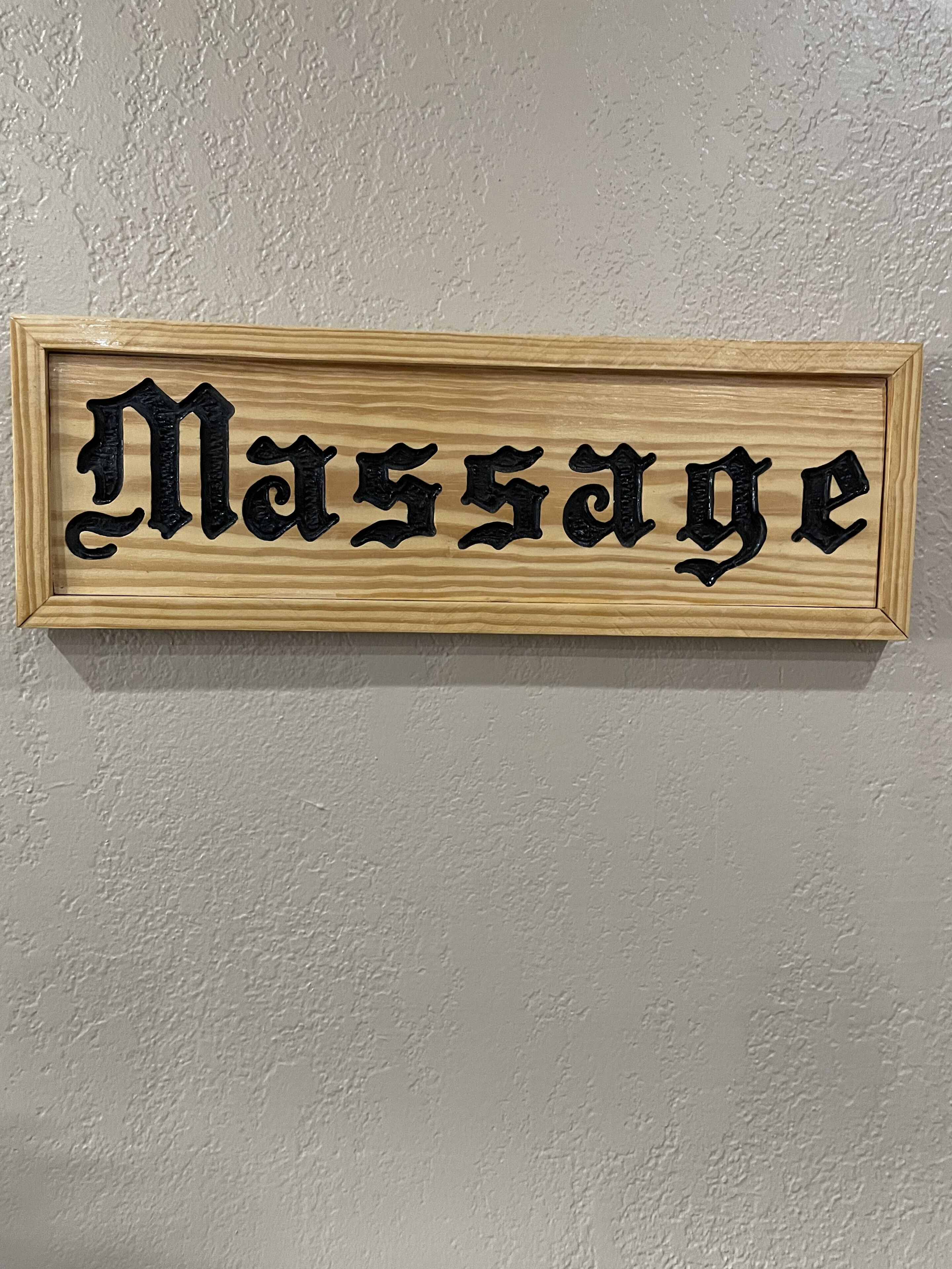 A wooden sign with the word "Massage" in black lettering.