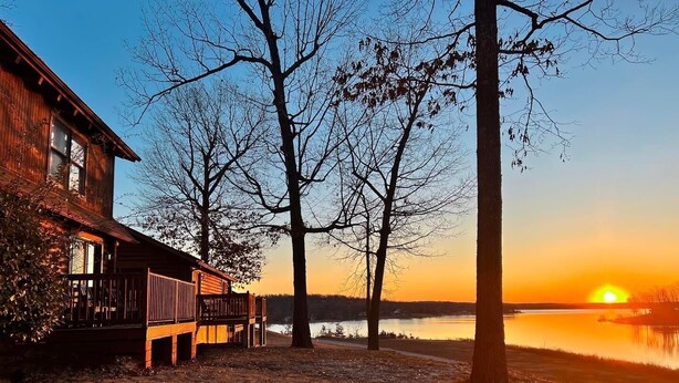 A cabin with a deck overlooking a lake at sunset. - Crown Point Resort (Horseshoe Bend)