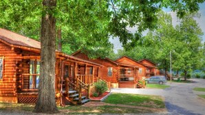 A row of log cabins with a gravel driveway and a car parked nearby. - Crown Point Resort (Horseshoe Bend)