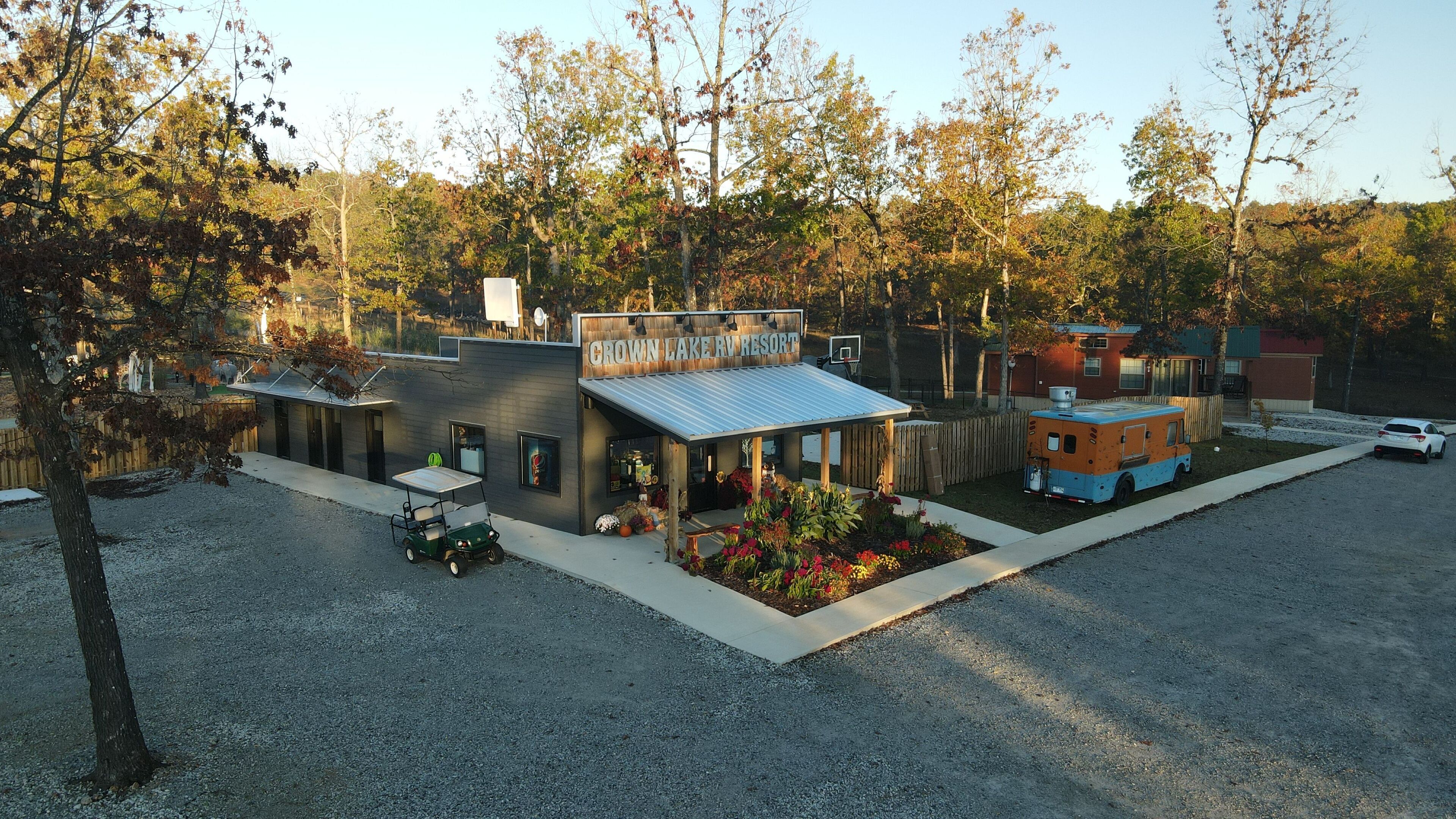 A modern RV resort with a covered patio, a small building with a sign, and a colorful RV.