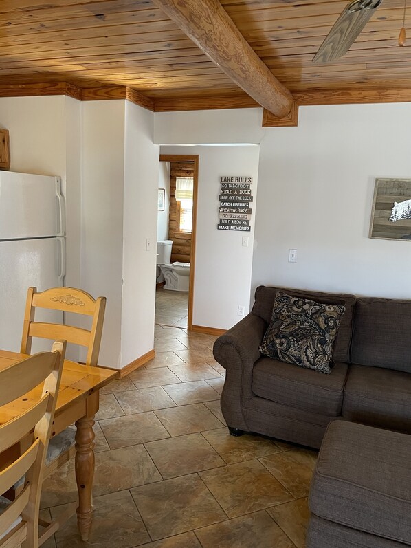 Un salon chaleureux avec une table à manger en bois, un canapé marron et un sol carrelé.