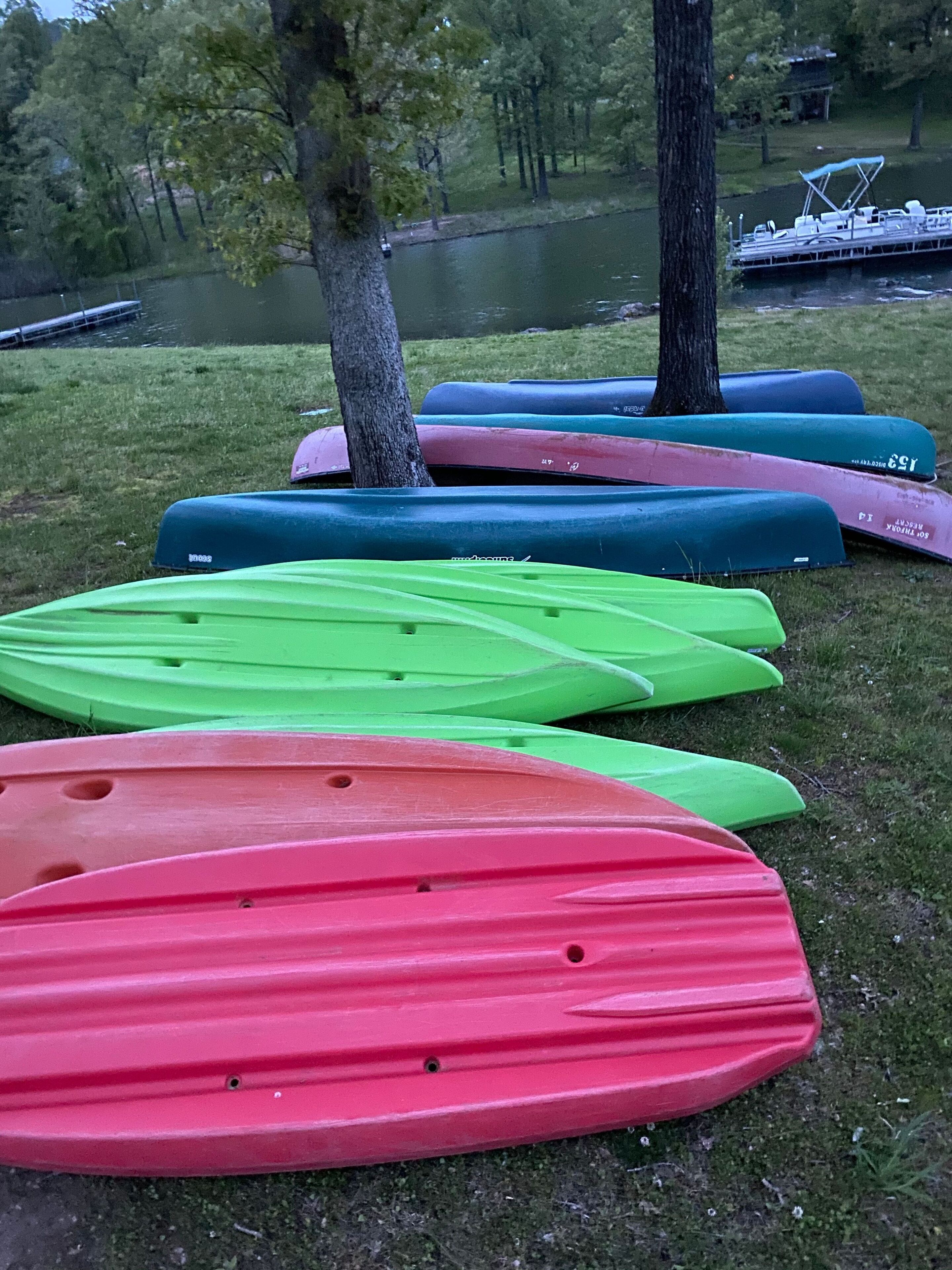 Un área verde con varios kayaks de colores alineados.