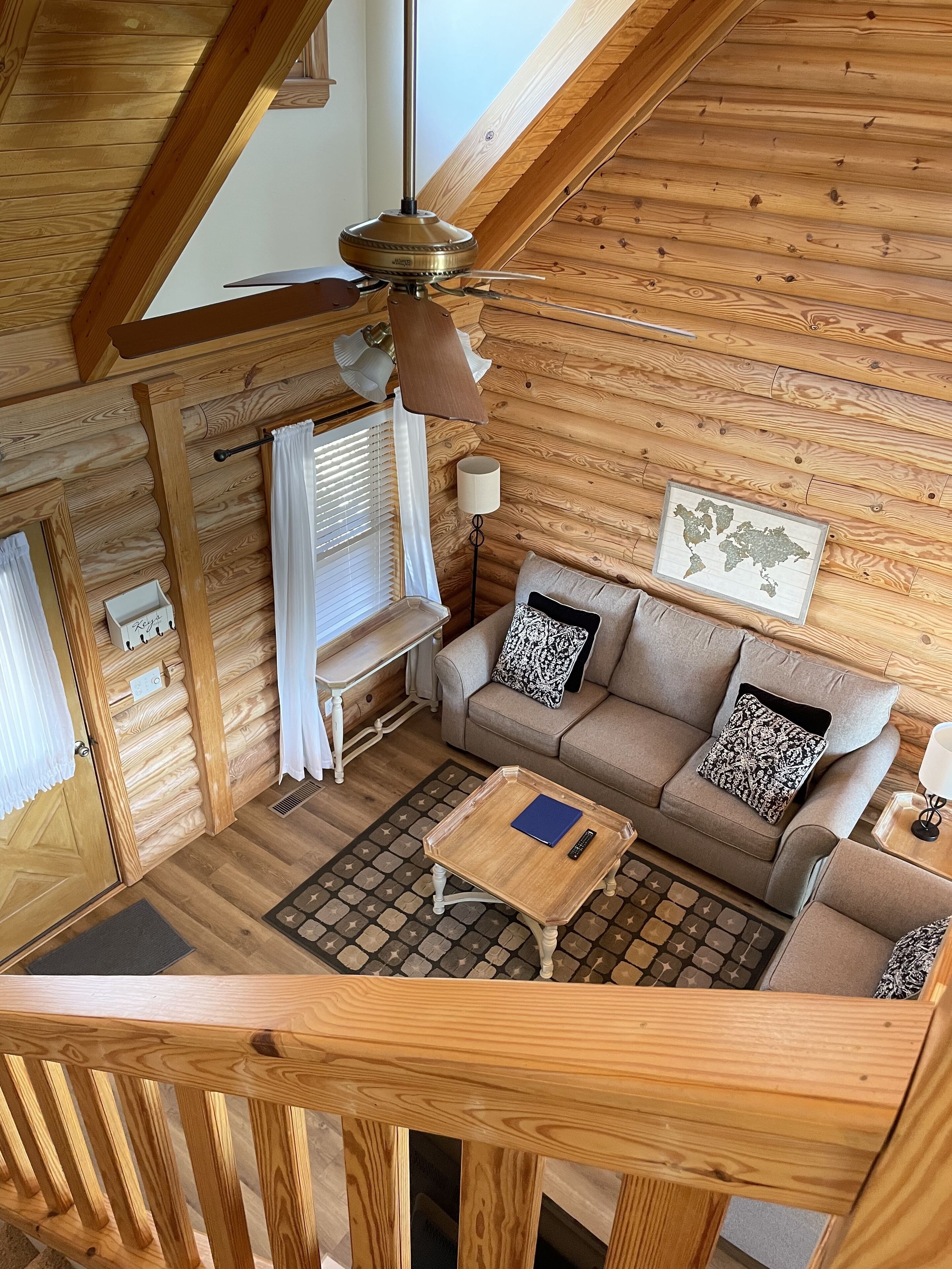 A cozy wooden cabin interior with a sofa, a coffee table, and a map on the wall.