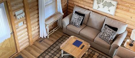 A cozy wooden cabin interior with a sofa, a coffee table, and a map on the wall.