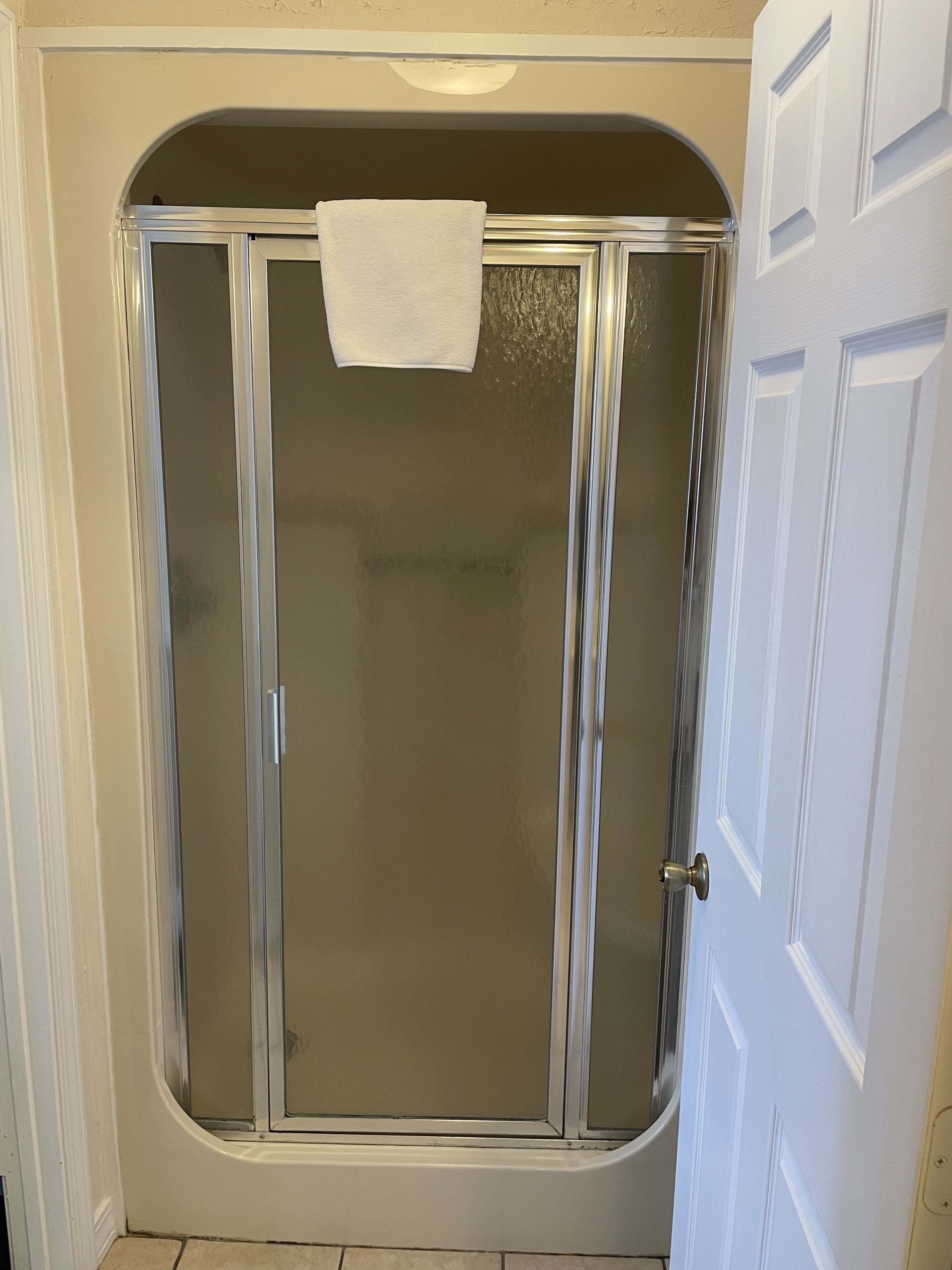 A shower enclosure with a glass door and a towel hanging on the handle.