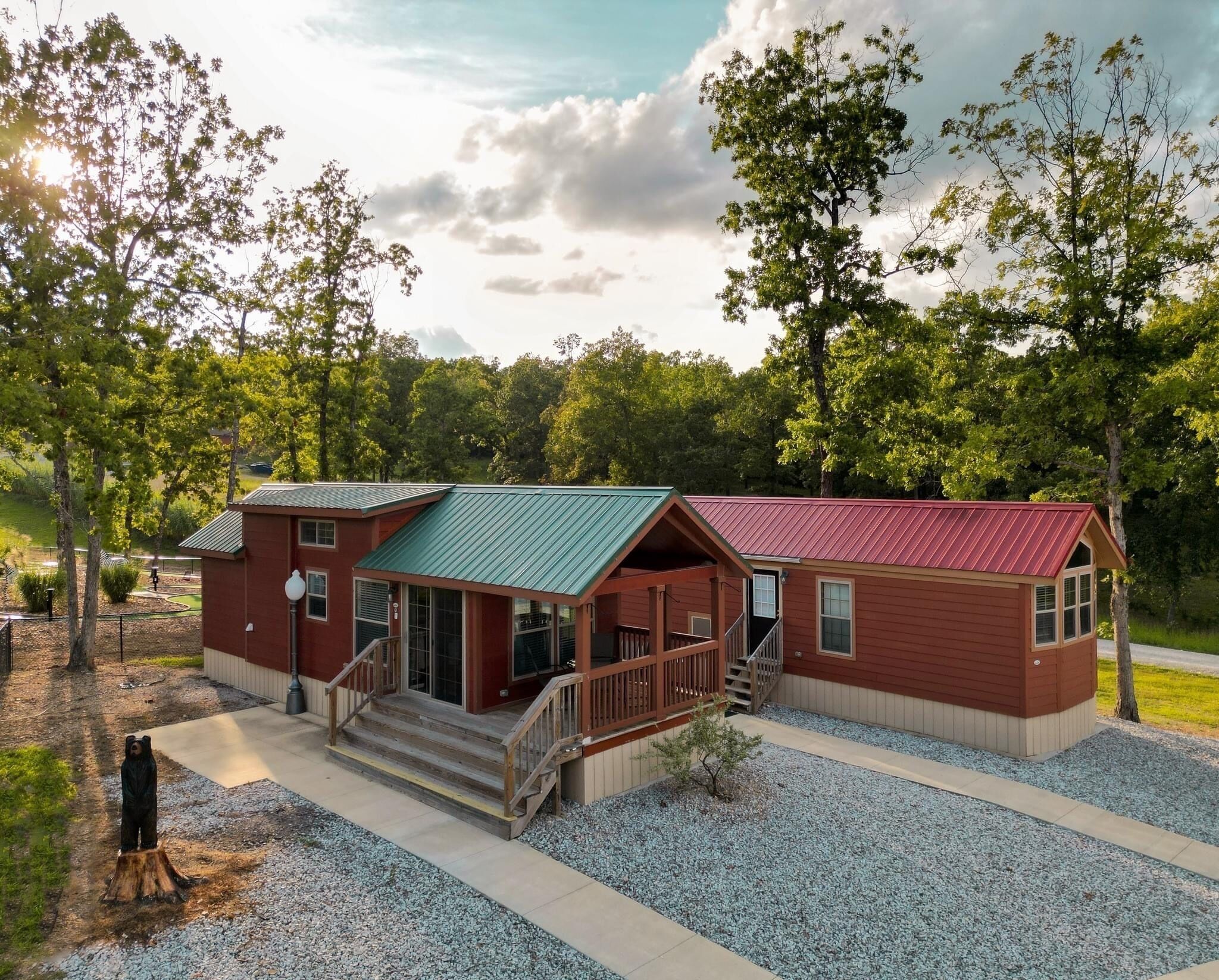 A two-story cabin with a porch and a covered outdoor area, surrounded by trees.