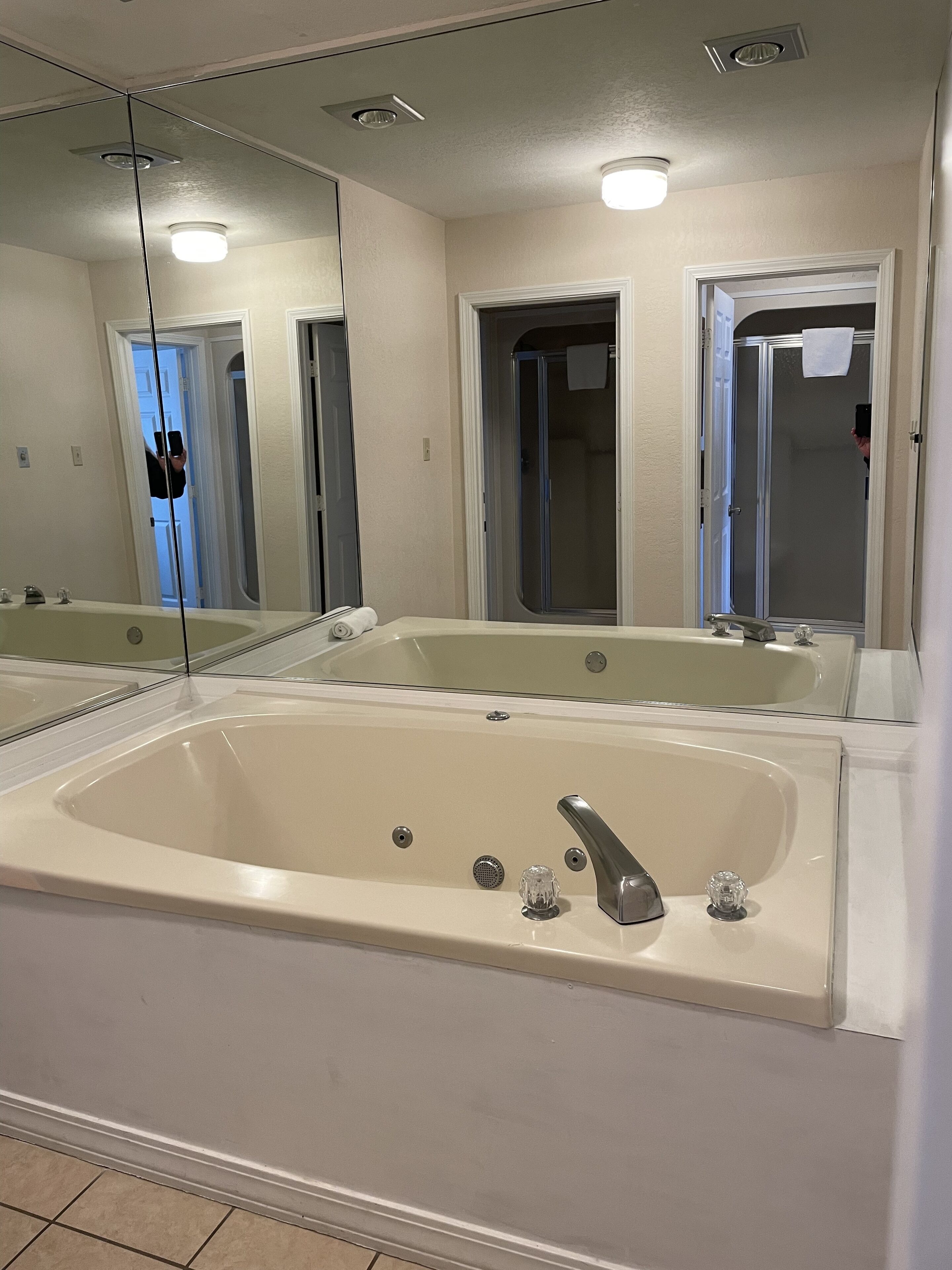 A bathroom with a large bathtub, a shower, and a mirror.