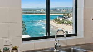 Cozinha com janela vista para a praia e edifícios.