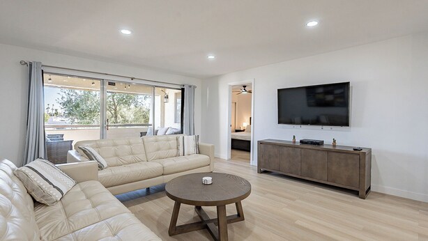 Un salon moderne avec un canapé d’angle beige, une table basse ronde et un téléviseur à écran plat posé sur un meuble en bois.