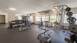 Une salle de sport équipée de divers appareils d’exercice, notamment des haltères, des tapis de course et des appareils de musculation.