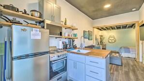 A compact kitchen with a refrigerator, stove, oven, and wooden shelves. - Walk to Ocean! Downtown Long Beach Studio (Long Beach)