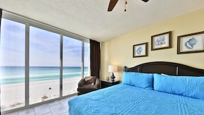 Un dormitorio con una cama grande, vista a la playa y cuadros en la pared.