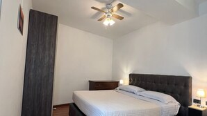 A bedroom with a bed, a nightstand, a ceiling fan, and a wooden floor. - Luxury apartment historic center, Air Conditioning, Wi-Fi, Jacuzii, garage.   (Bellagio)