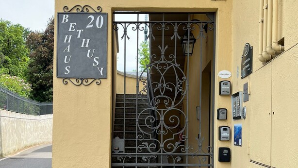 A building entrance with a metal gate, a sign reading "BETHUSIA HOUSE", and a small garden area with plants. - Luxury apartment historic center, Air Conditioning, Wi-Fi, Jacuzii, garage.   (Bellagio)