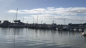 A marina with boats docked, calm water, and a clear sky with clouds. - Location! Value! Steps to Beach! Perfect for Summer Trip- Spacious 4-5BR Retreat (Hampton)